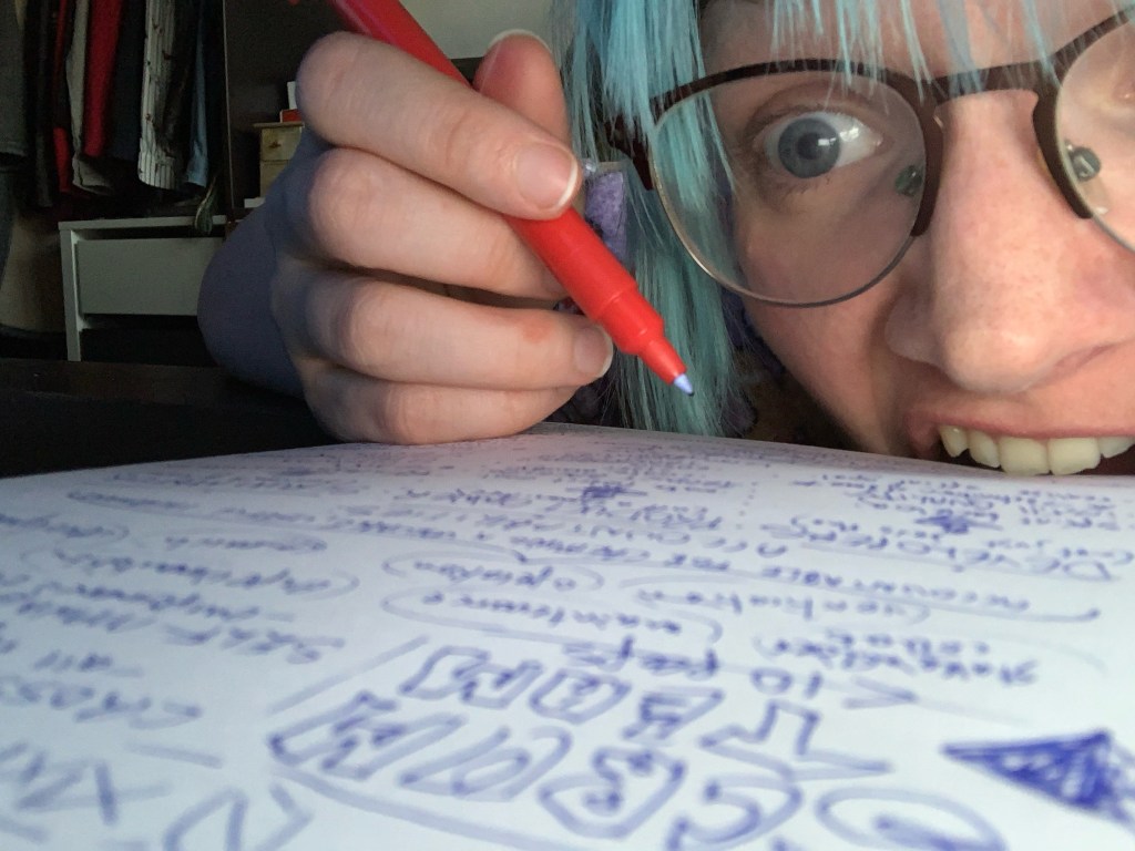 Photograph of me writing notes while biting the paper I am writing on in frustration.